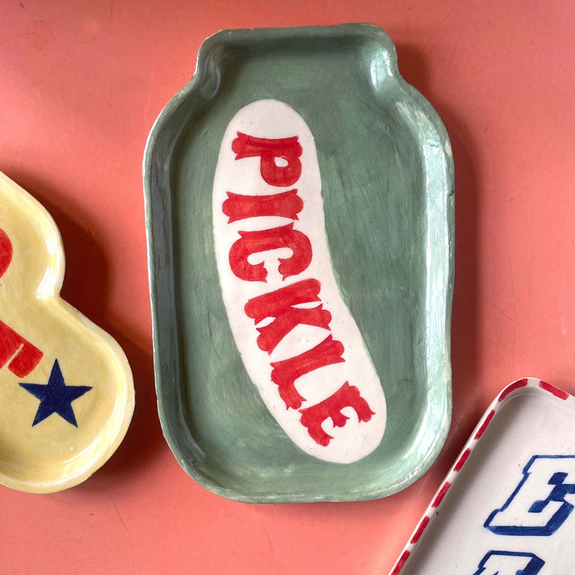 Green ceramic dish with 'Pickle' text on a pink background